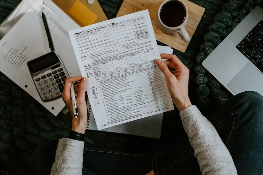 hands-holding-tax-forms-with-calculator-and-laptop-8xrytoyqdru