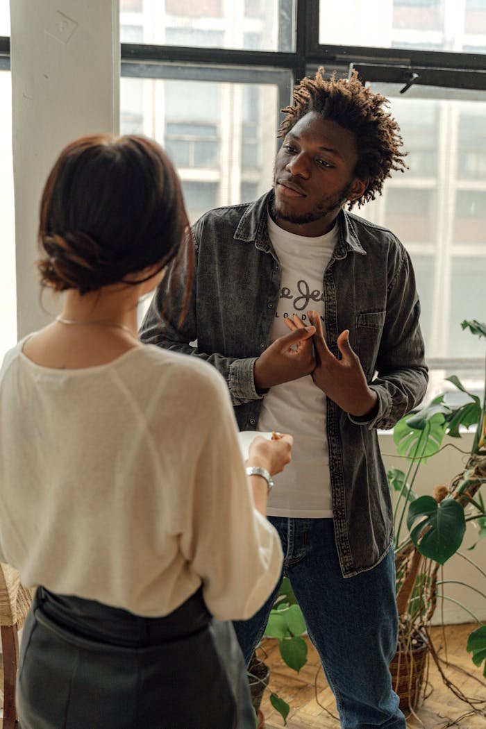 Two adults engage in a casual conversation in a bright, modern office environment.